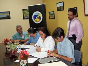 Agriculture Secretary Myrna Comas (center) signs agreements with coffee farmers. 