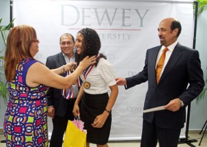 One of this year's outstanding students receives an achievement medal, as Dewey University President Carlos Quiñones-Alfonso (right) looks on.