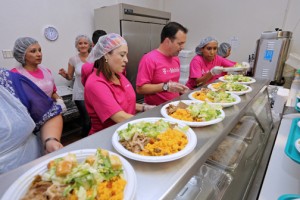 T-Mobile employees line up the plates of typical Puerto Rican Christmas fare for the annual lunch at La Fondita de Jesús.